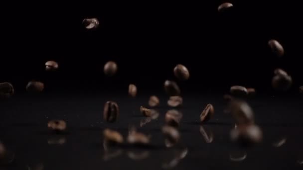 Coffee beans fall on a solid black surface — Stock Video