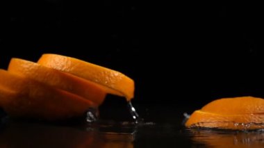 su ile kaplı siyah yüzeyinde portakal dilimleri düşmek