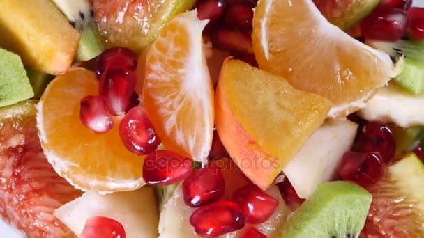 Blick von oben auf einen Obstsalat mit Mandarine, Orangen, Kiwi, Granatapfel, Feigen, Banane und Pfirsichen — Stockvideo