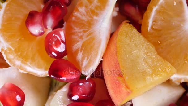 Bovenaanzicht van een fruitsalade met Mandarijn, sinaasappels, kiwi, granaatappel zaden, vijgen, bananen en perziken — Stockvideo