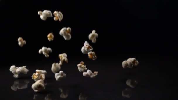 Popcorn fällt auf schwarze Fläche — Stockvideo