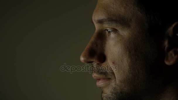 Ansiktet av en man som sitter i mörkret framför en datorskärm — Stockvideo