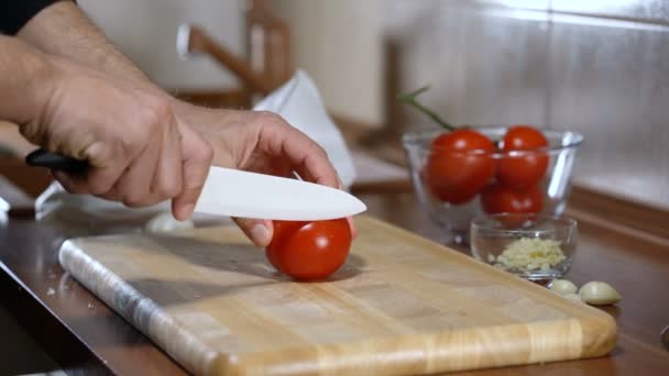 Man snijdt een tomaat voor het koken van bruschetta — Stockvideo