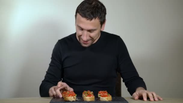 De man met een honger eet bruschetta — Stockvideo