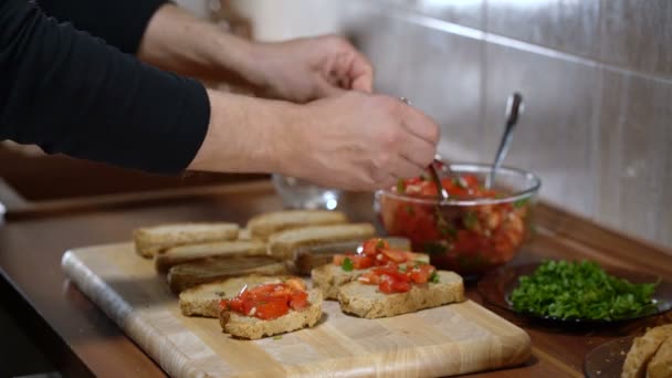 Kişi bruschetta yemek pişirmek için ekmek üstüne malzemeler koyar — Stok video