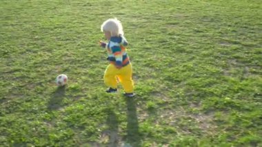 Bir buçuk yaşındaki çocuk sevinçle top sahada kovalıyor.