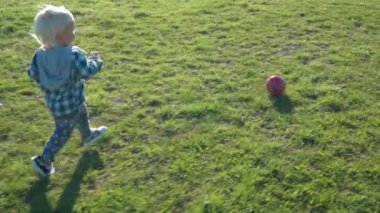 Bir buçuk yaşındaki çocuk sevinçle top sahada kovalıyor.