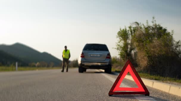 Een man loopt naast een gebroken auto wachten op hulp — Stockvideo