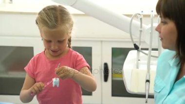 Küçük kız dişçi ofisinde oturuyor.