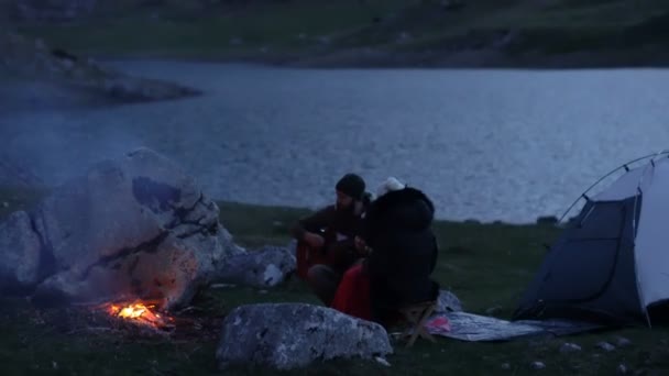 Un par de viajeros al atardecer cerca de una fogata — Vídeos de Stock