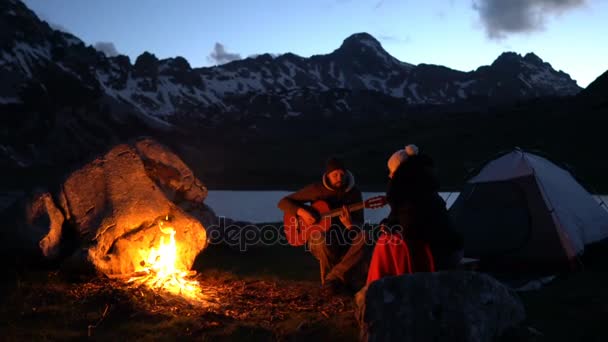 Un par de viajeros al atardecer cerca de una fogata — Vídeos de Stock