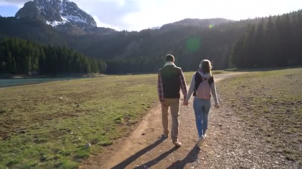 Νεαρό ζευγάρι περπάτημα κατά μήκος της λίμνης — Αρχείο Βίντεο