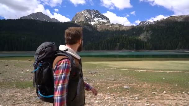 Viajante com uma mochila andando ao longo do lago — Vídeo de Stock