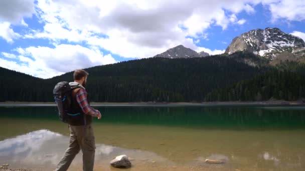 湖に沿って歩いてバックパック旅行者 — ストック動画