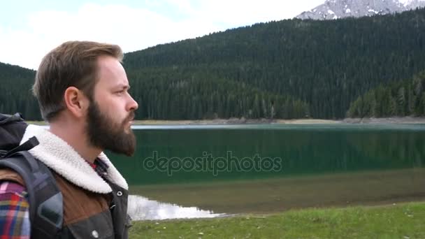 Мандрівник з рюкзаком, що йде уздовж озера — стокове відео