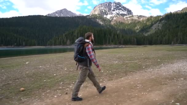 Reiziger met een rugzak wandelen langs het meer — Stockvideo