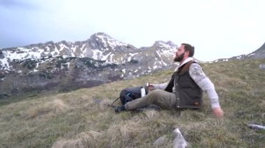 Uzun yürüyüşe çıkan kimse oturur ve bir termos sıcak çay içer