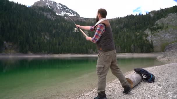 Jongeman gegoten een spinnen op de oevers van de schilderachtige Lake — Stockvideo