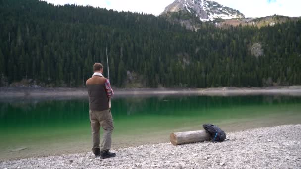 Jeune homme jeté une filature sur les rives du lac pittoresque — Video