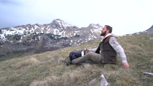 Randonneur assis et boit le thé chaud d'un thermos — Video