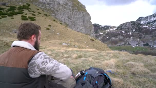 Wanderer sitzt und trinkt heißen Tee aus Thermoskanne — Stockvideo