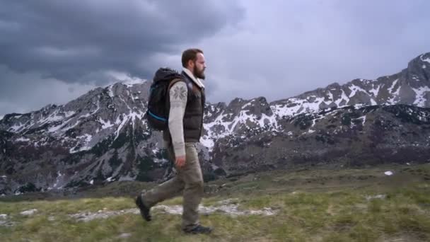 Caminhante indo ao longo da encosta gramada — Vídeo de Stock