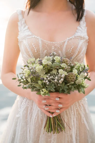 Svatební kytice v rukou nevěsty se spoustou zeleně — Stock fotografie