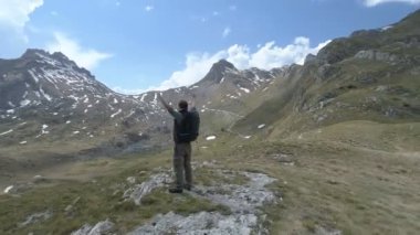 Uzun yürüyüşe çıkan kimse üstte duruyor ve zafer hareketle ortaya çıkar ellerini tutar