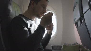 genç adam yemeğini uçağın içinde yiyor.