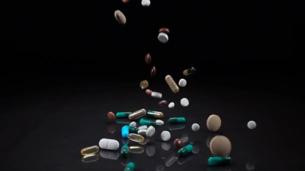 A large and varied assortment of pharmaceutical drugs or vitamin supplements fall against a black background — Stock Video