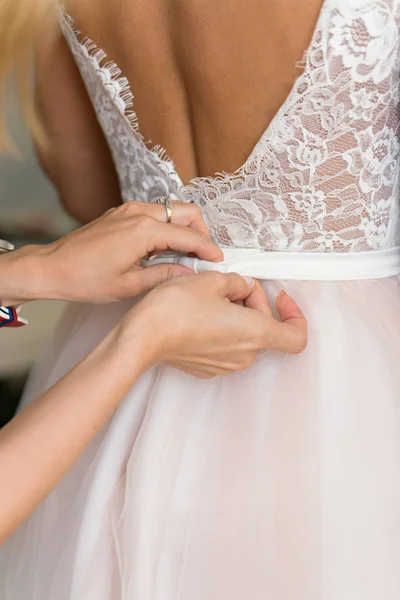 Mãos de damas de honra que ajudam a pôr um vestido — Fotografia de Stock