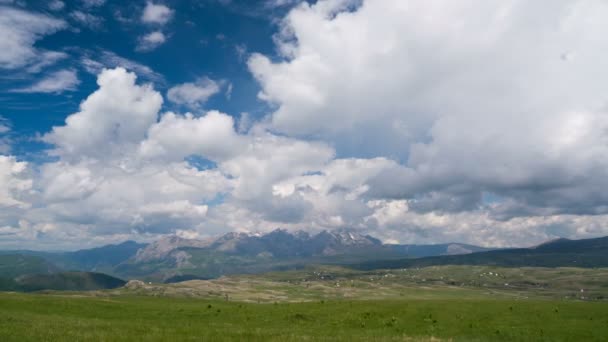 Clouds over the green meadow with majestic mountains in the background — Stock Video