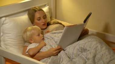 Anne ve bebek evlat yatakta kitap okuma