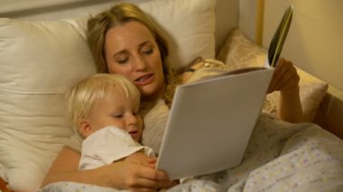 Anne ve bebek evlat yatakta kitap okuma