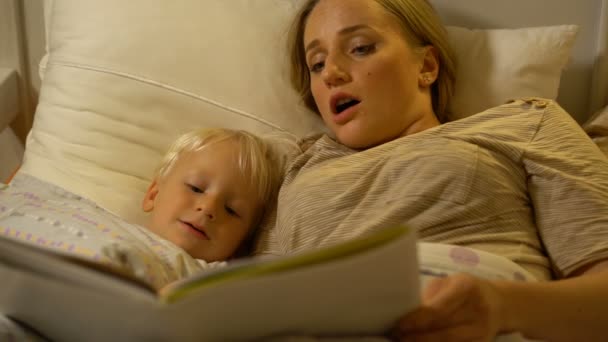 Mère et bébé fils lisant un livre au lit — Video