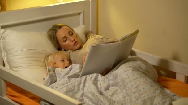 Mor och baby son en bok i sängen — Stockvideo