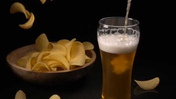 Burgonya chips egy fából készült tálba öntjük, és sört öntenek a pohárba — Stock videók