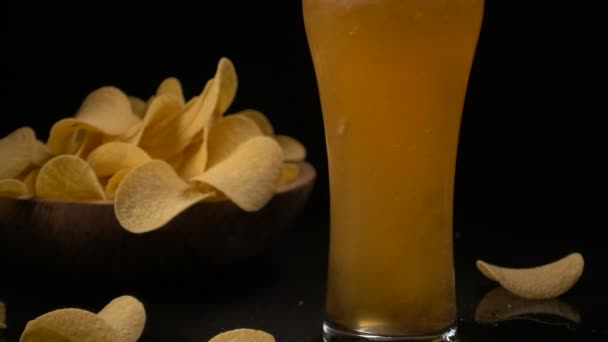 Kartoffelchips werden in eine hölzerne Schüssel gegossen und Bier in ein Glas — Stockvideo