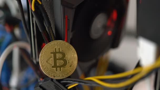 Bitcoin no fundo de uma placa gráfica em um rack para mineração de criptomoedas — Vídeo de Stock