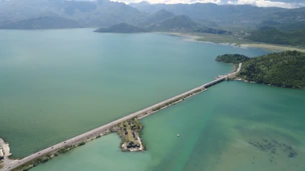 Luchtfoto op de dam met spoorweg en autoverkeer brug leidt door het waterlink meer. Routeren tussen Podgorica Adriatische kust. — Stockvideo