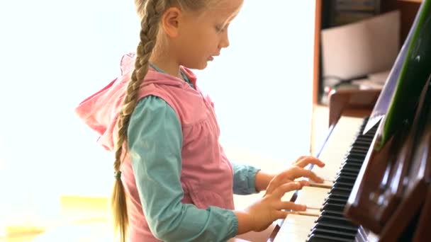 Маленькая девочка учится играть на пианино — стоковое видео