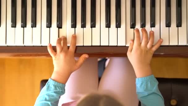 Маленька дівчинка вчиться грати на піаніно — стокове відео