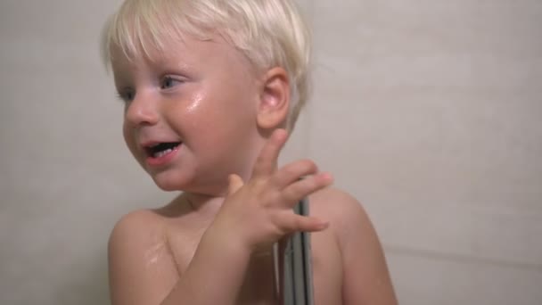 A two year old boy washes in the shower — Stockvideo