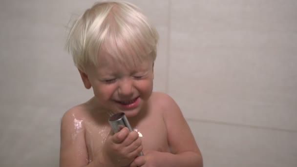 A two year old boy washes in the shower — Stockvideo