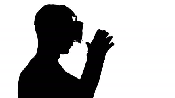 Силуэт человека в очках виртуальной реальности, смотрящего видео — стоковое видео