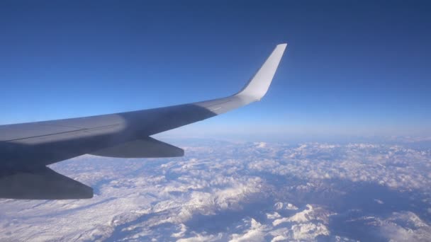 Крыло самолета видно в окне самолета над облаками — стоковое видео