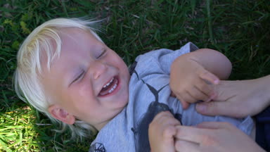 Anne bebek gıdıklıyor ve gülüyor çim üzerinde yalan