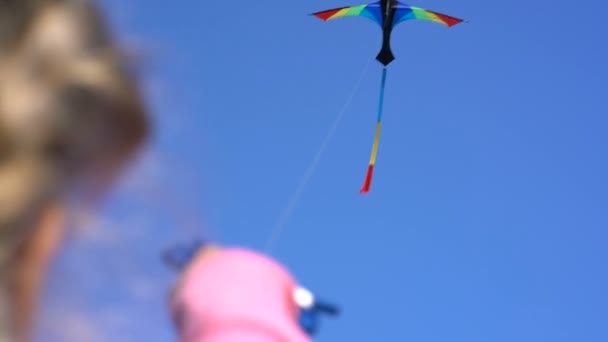 Een vlieger in de lucht op een heldere dag in de hand van de meisjes — Stockvideo