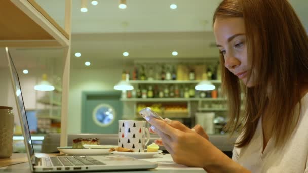 Leuke vrouw met behulp van een laptop in een café — Stockvideo