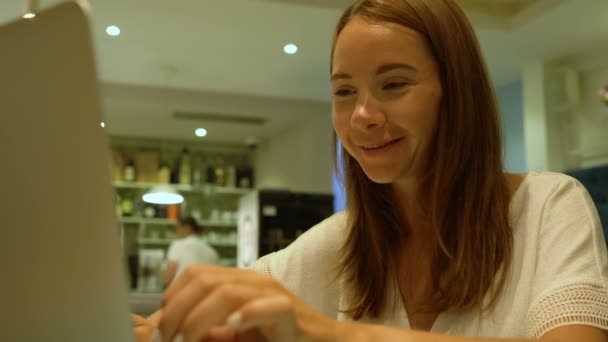 Χαριτωμένο γυναίκα χρησιμοποιώντας ένα σημειωματάριο σε ένα καφέ — Αρχείο Βίντεο